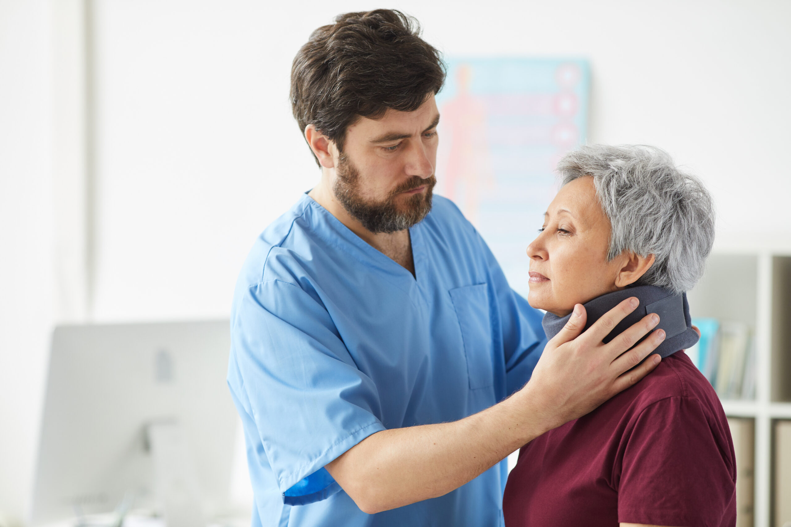 Alt text: Nurse adjusting a neck brace on a senior patient